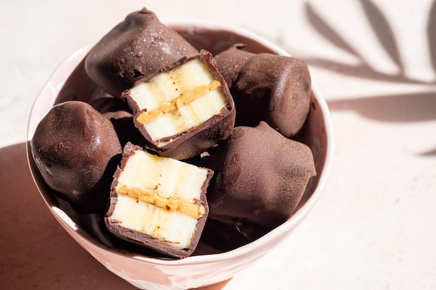 Bevroren gezond dessert. Bananenhapjes met pure chocolade en pindakaas