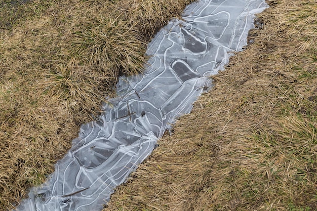 Bevroren ijs in een plas op een veld in het vroege voorjaar