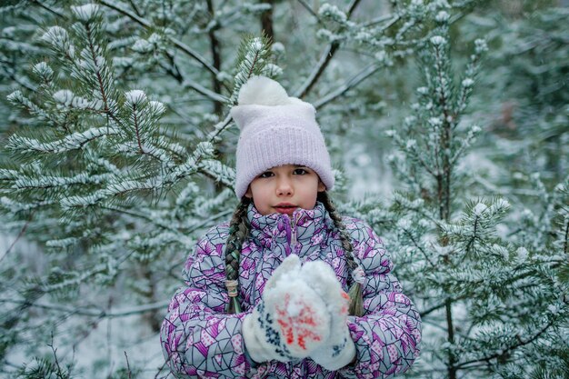 Bevroren meisje in warme kleren loopt door het bos met het eerste langverwachte sneeuwwinterwonderland