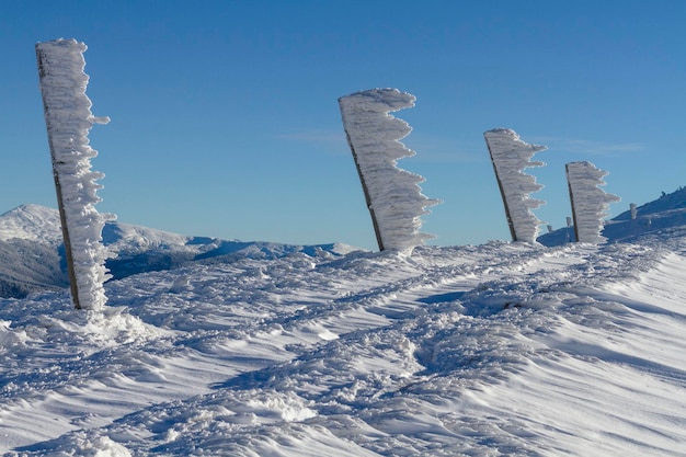 Bevroren pilaren met geblazen sneeuw en ijspegels sneeuwvlaggen in de bergen