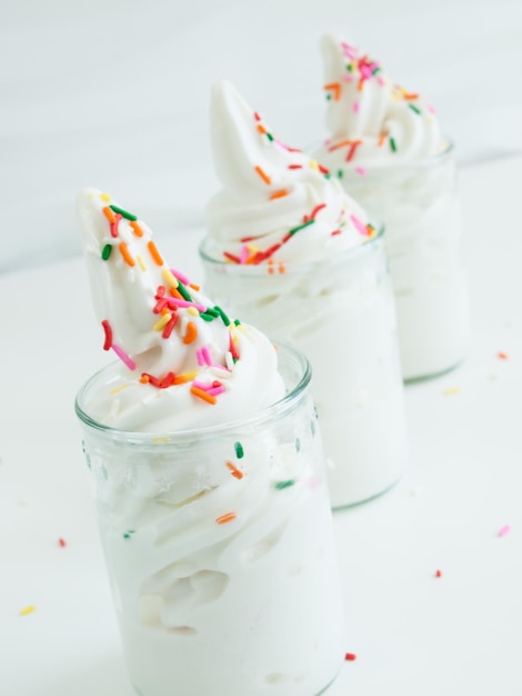 Bevroren soft-serve yoghurt in glas op witte achtergrond.