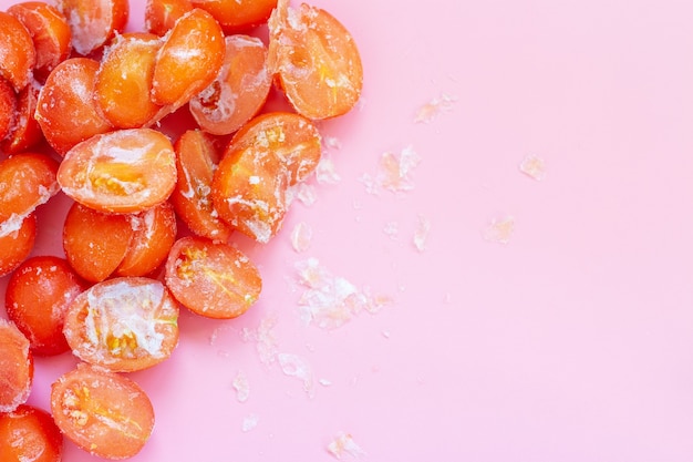 Bevroren tomaten op een roze achtergrond met kopieerruimte bovenaanzicht.