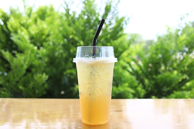 Bevroren vers drankje honing citroen frisdrank verfrissing sap in het glas op houten tafel en groene boom achtergrond