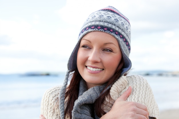 Bevroren vrouw met sjaal en kleurrijke hoed die zich op het strand bevinden