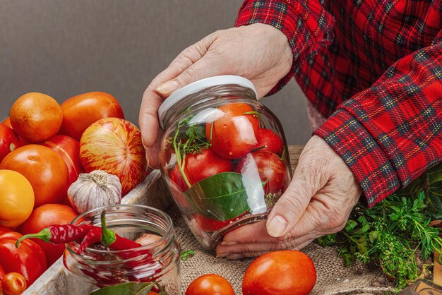 Bewaarde seizoensgroenteconcept Oogst van tomaat, chili, groene ui en knoflook Vrouwenhanden bereiden ingrediënten voor het kookproces van ingeblikt voedsel Gezonde recepten thuiskeuken kopieerruimte