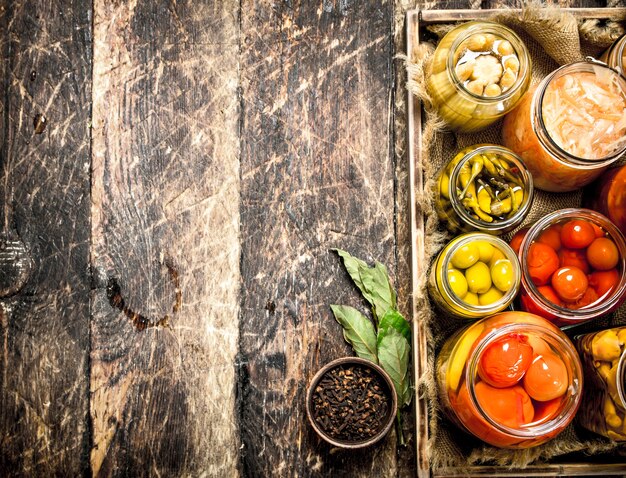 Bewaart voedsel met groenten en champignons op een oud bakje. Op een houten tafel.
