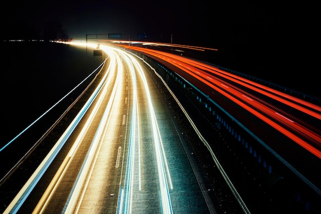 Bewegende autolichten op snelweg 's nachts lange blootstelling