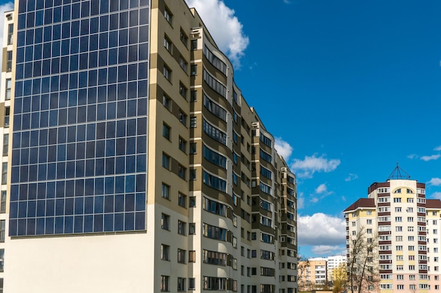 Beweging van wolken tegen de achtergrond van een modern energiezuinig gebouw Woongebouw met meerdere verdiepingen met zonnepanelen op de muur Hernieuwbare energie in de stad