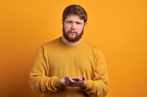 Bewildered man with thick ginger beard raises eyebrows reacts on fake news from friend looks directly at camera dressed in casual t shirt isolated over white background facial expressions