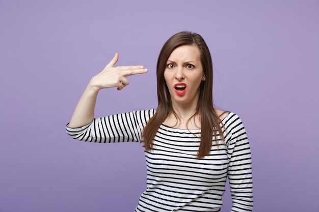 Bewildered puzzled young woman in casual striped clothes posing isolated on violet purple background. people lifestyle concept. mock up copy space. point fingers to head as if she about shoot herself