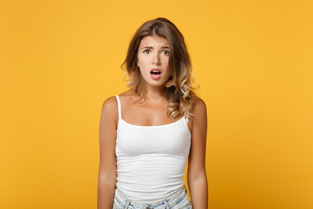 Bewildered young woman girl in light casual clothes posing isolated on yellow orange wall background, studio portrait. People sincere emotions lifestyle concept. Mock up copy space. Looking camera.