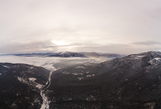 Bewitching view of beautiful mountain cliffs covered with snow and fog on a cloudy winter day. Ski resort. The concept of tourism in the northern countries