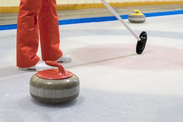 Bezem en steen voor curling op ijs van een indoor ijsbaan.