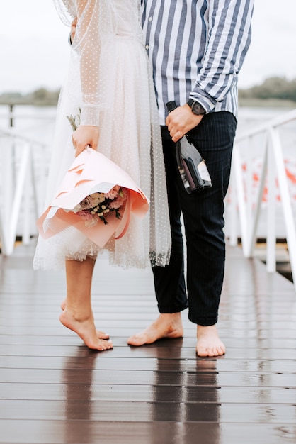 Bezinksel van de net getrouwd op de kade. Benen van de bruid en bruidegom op blote voeten op de pier.