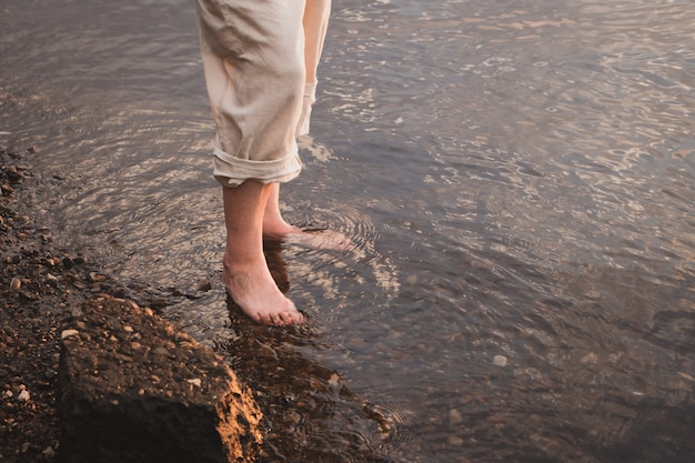 bezinksel van een vrouw die in het water van de rivier of de zee loopt bij zonsondergang zomertijd