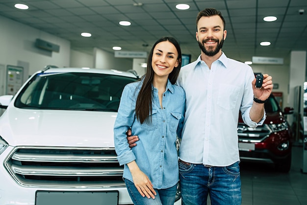 Bezoek de dealer Gelukkig jong stel kiest en koopt een nieuwe auto voor het gezin