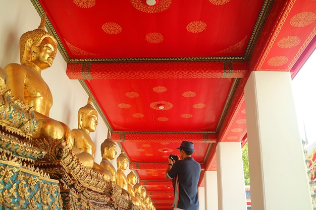 bezoeker die foto's maakt van een groep zittende boeddha's in een tempel in Bangkok