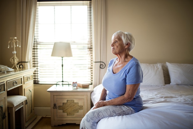 Bezorgd senior vrouw zittend op bed in de slaapkamer thuis