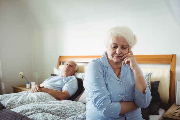 Bezorgd senior vrouw zittend op bed