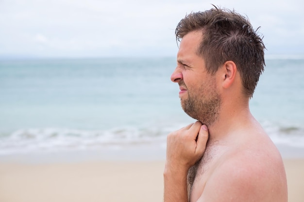 Bezorgde blanke man zuigt zijn duim op het tropische strand