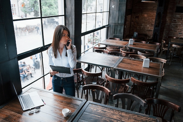 Bezorgde blik. Zakenvrouw in officiële kleding is overdag binnenshuis in café.