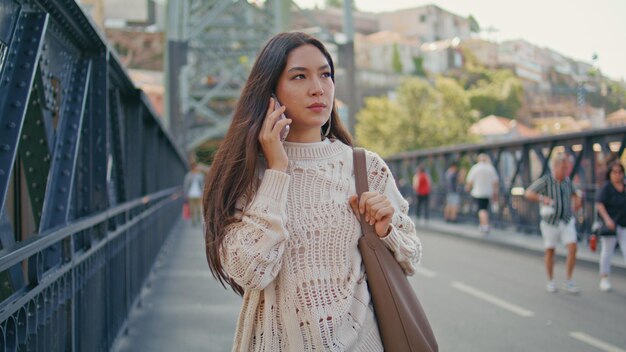 Foto bezorgde dame die aan het bellen is, wandeling over de brug, close-up dame die aan de telefoon praat.