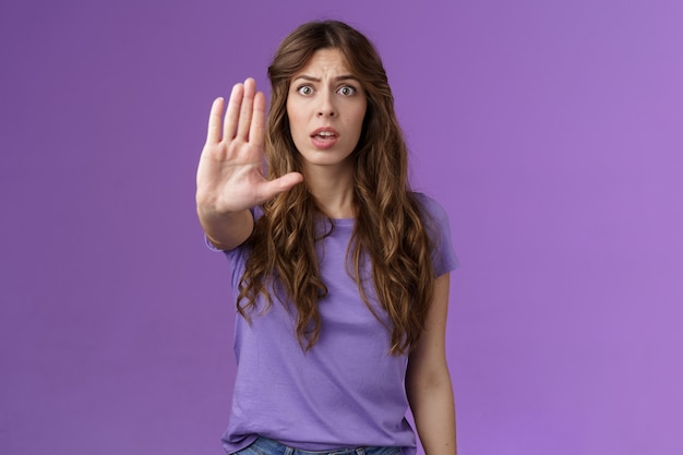 Bezorgde geschokte vrouw met krullend haar hijgend staren camera angstig trekken hand stopbord smeken einde pro...