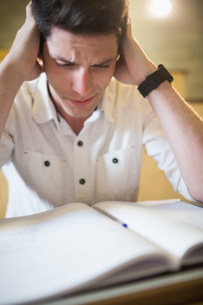 Bezorgde mannelijke student tijdens examen in collegezaal