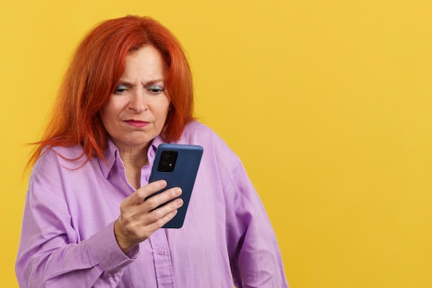 Foto bezorgde roodharige volwassen vrouw die een mobiele telefoon gebruikt