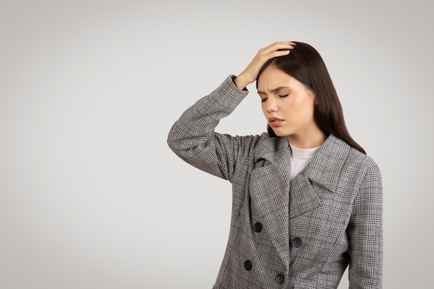 Bezorgde vrouw met hand op haar hoofd die naar de vrije ruimte kijkt