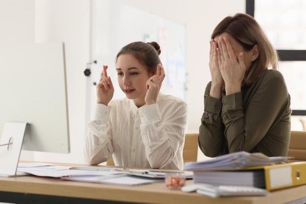 Bezorgde vrouwelijke werknemers hopen op succes van nieuw gezamenlijk project jonge vrouw kruist vingers