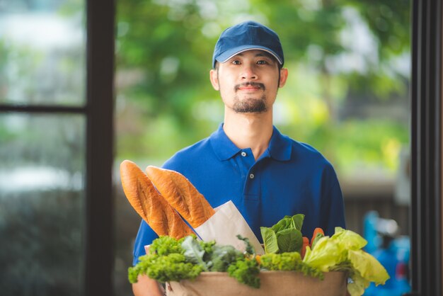 Bezorger geeft de tas van de kruidenierswinkel aan de vrouw aan de voorkant van haar huis