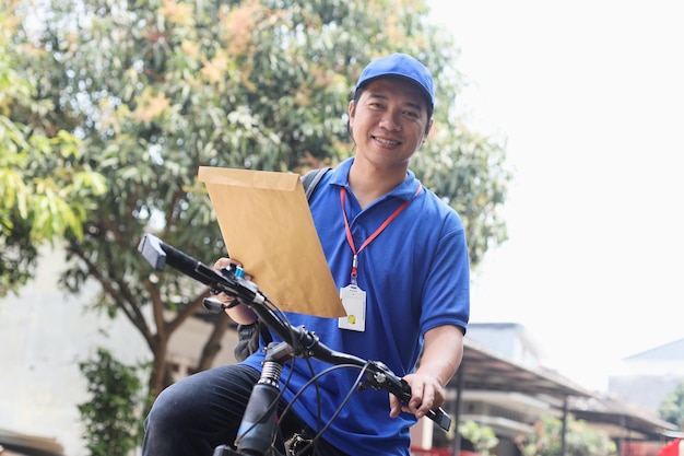 bezorger in blauw uniform brengt post om te verzenden tijdens het fietsen.