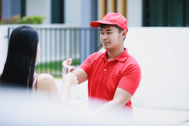 Bezorger in een rood t-shirt met voedselpakket