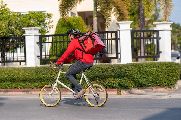 Bezorger in rood uniform fietsen om producten thuis bij klanten af te leveren.