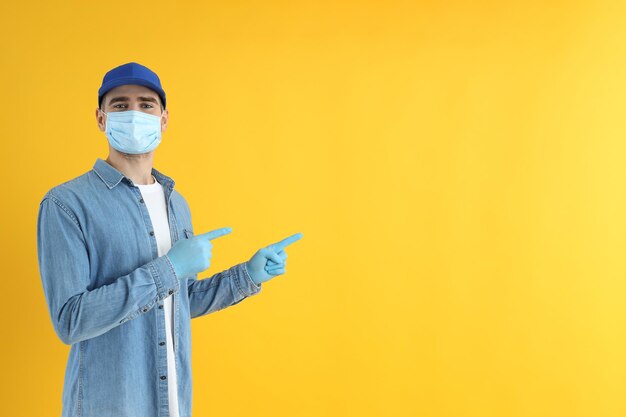 Bezorger met masker en handschoenen op gele achtergrond