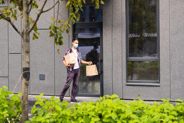 Bezorger met papieren zak met eten, bezorger van eten met beschermend masker