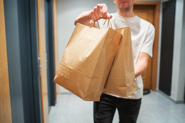 Bezorger met papieren zak met eten bij de ingang