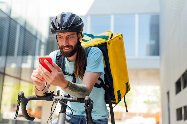 Bezorger op fiets kijken naar smartphone