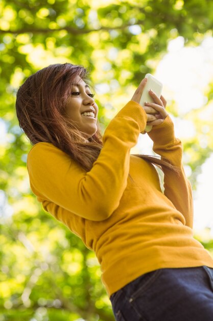 BHeautiful woman text messaging in park