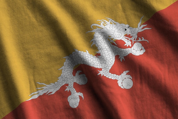 Bhutan flag with big folds waving close up under the studio light indoors The official symbols and colors in banner