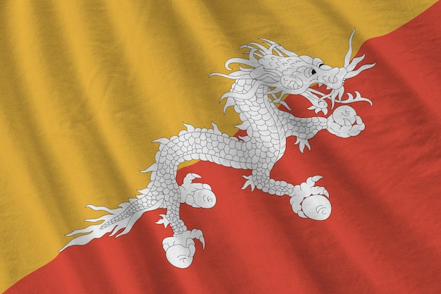 Bhutan flag with big folds waving close up under the studio light indoors The official symbols and colors in banner