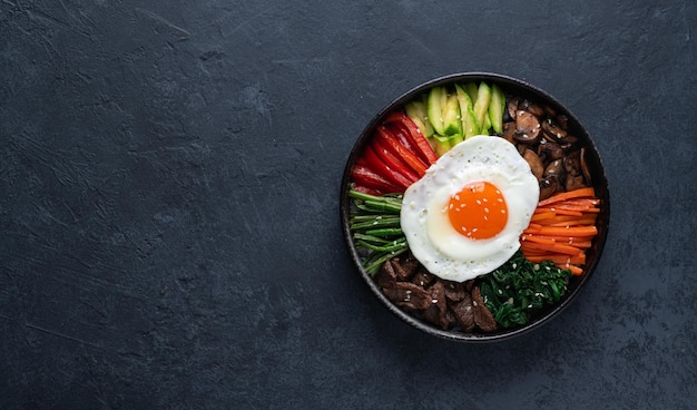 Bibimbap su uno sfondo di cemento scuro tradizionale piatto coreano vista dall'alto spazio di copia