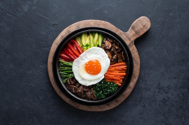 Foto bibimbap su uno sfondo di cemento scuro tradizionale piatto coreano vista dall'alto