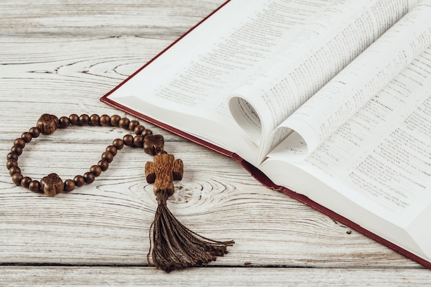 Bible and a crucifix on an old wooden table