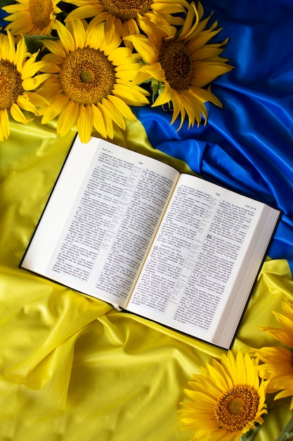 Photo bible holy writ and sunflowers on background of flag of ukraine