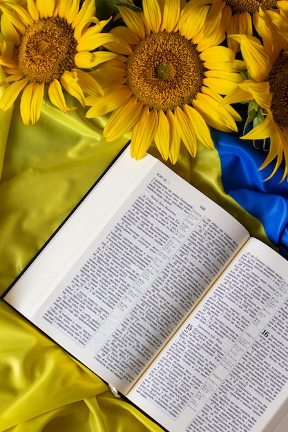 Bible Holy Writ and sunflowers on background of flag of Ukraine