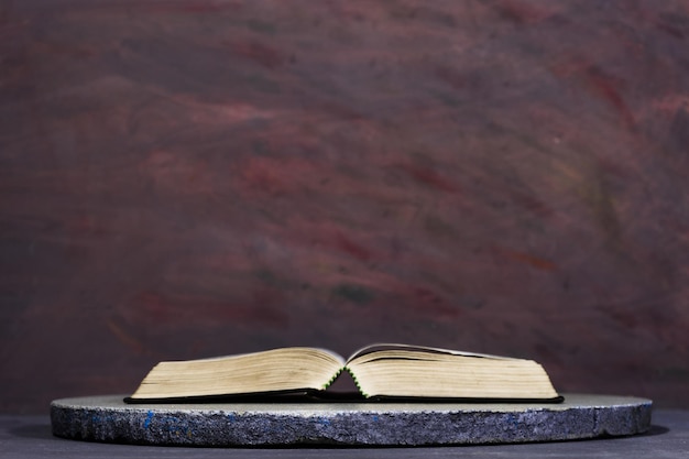 Bible on a round white table Beautiful darkred background Religious concept