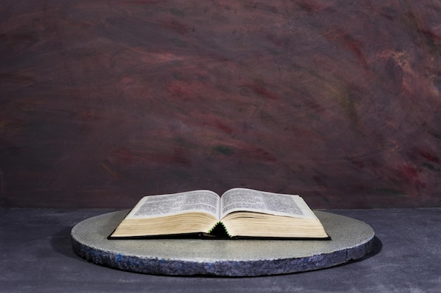 Библия на круглом белом столе Красивый темный фон Религиозная концепция