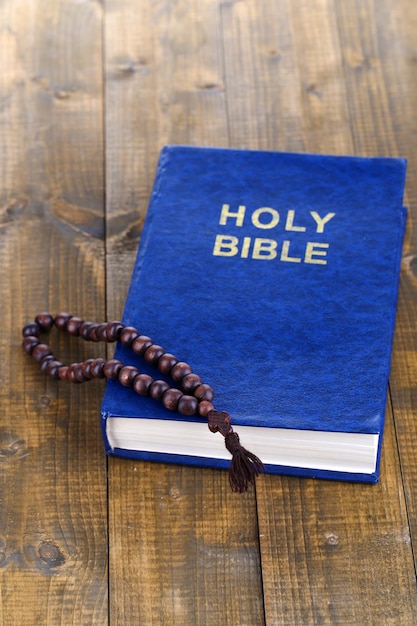 Bible with cross on wooden table closeup